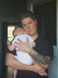 Woman holding a baby and seen through a screen door