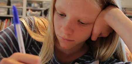 Girl writing at a desk with a pencil