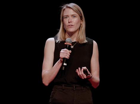 woman in a black dress speaking to an audience