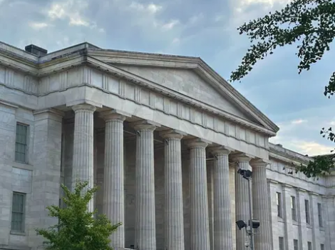 Photograph of the National Portrait Gallery's exterior against a blue sky and clouds with its central columns in the center.